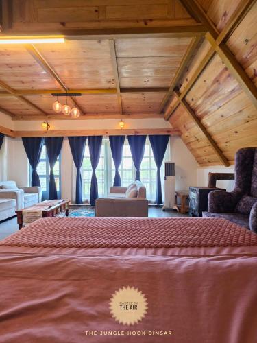 a bedroom with a large bed with blue curtains at The Jungle Hook Binsar in Almora
