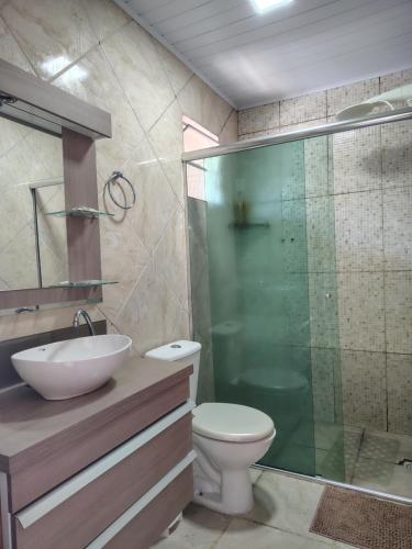 a bathroom with a toilet and a glass shower at Condomínio Central Meu Cantinho in Uruguaiana