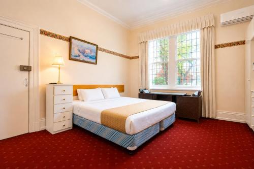 a bedroom with a bed and a desk and a window at Georgian Court Inn in Melbourne
