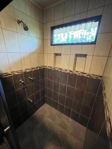 a bathroom with a shower with a window at La casa de MR in Sarapiquí