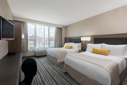 a hotel room with two beds and a flat screen tv at Wyndham Garden LaGuardia South in Queens