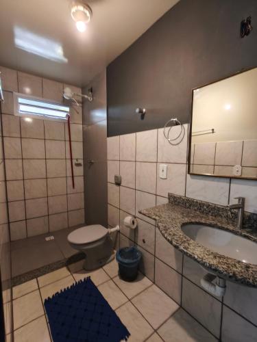 a bathroom with a sink and a toilet and a mirror at Pousada Ilha do sol in Piúma