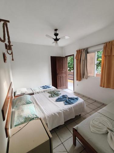 a bedroom with two beds and a window at Pousada Ilha do sol in Piúma