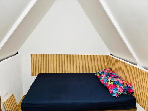 ein blaues Bett mit einem Kissen in einem Zimmer in der Unterkunft Faatiarau in Fakarava