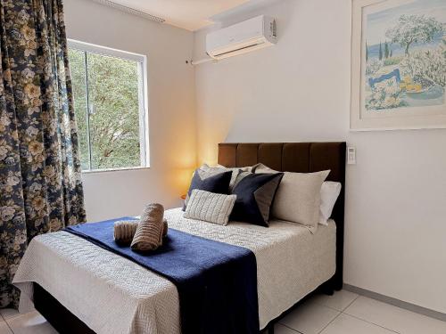 a bedroom with a bed with a blue blanket and a window at Centro, apê 2 Quartos com Ar | Garagem in Brusque