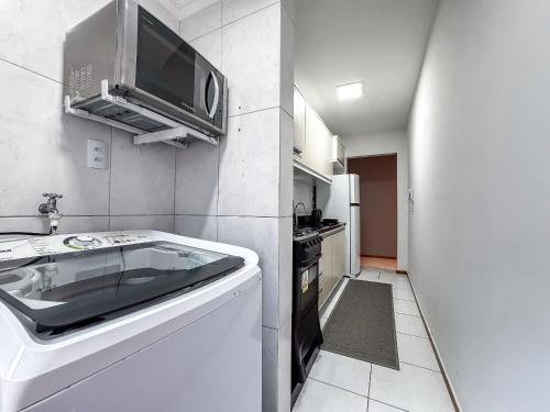a small kitchen with a microwave and a dishwasher at Centro, apê 2 Quartos com Ar | Garagem in Brusque