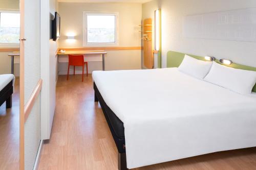 a bedroom with a large white bed and a desk at Ibis Budget Madrid Alcorcón Móstoles in Alcorcón