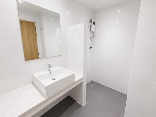 a white bathroom with a sink and a mirror at De Botan Bangna in Bangkok