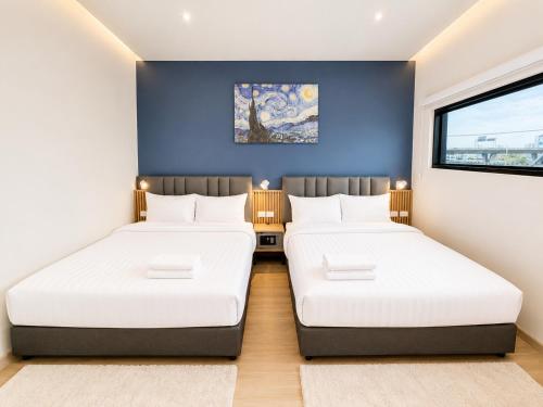 two beds in a room with a blue wall at De Botan Bangna in Bangkok