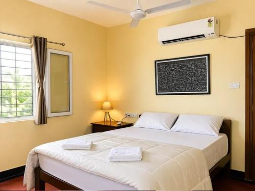 a bedroom with a large white bed and a window at Surya Villa Guesthouse in Auroville