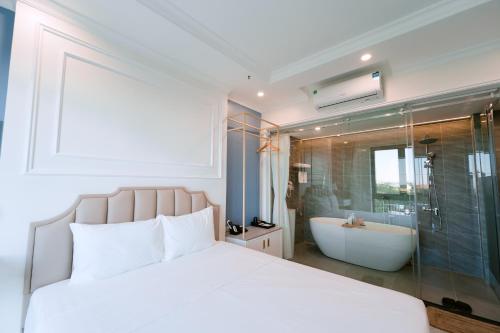 a bedroom with a white bed and a bath tub at Nhật Tân Hotel Triển Lãm VEC - Đông Anh in Dong Anh