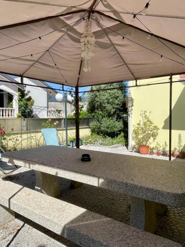 a stone bench with an umbrella on a patio at Casa Palma Hostel in Barcelos