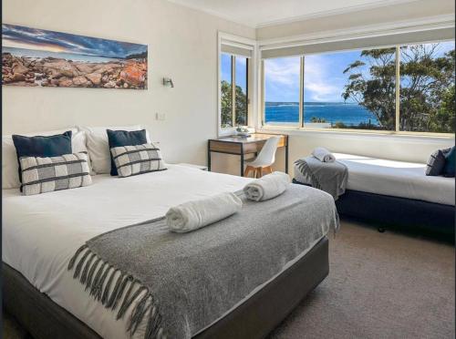 a bedroom with two beds and a large window at Bay View Escape in Binalong Bay