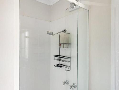 a shower with a glass door with a shelf at Bay View Escape in Binalong Bay