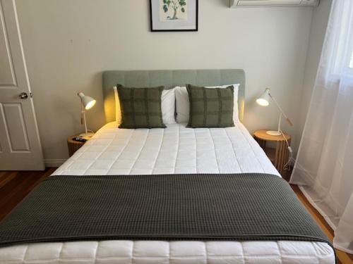 a bedroom with a large white bed with two lamps at The Arabella Motel in Wollongbar