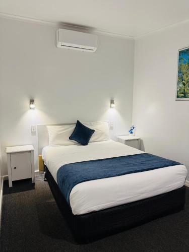 a bedroom with a large bed with a blue pillow at Bandicoot Motor Inn Hamilton in Hamilton