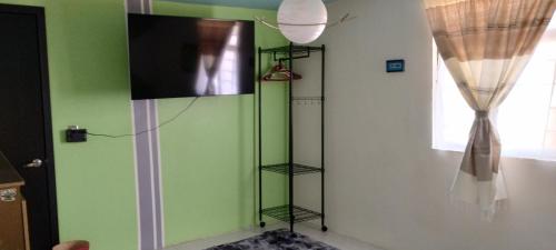 a room with a green wall with a television and shelves at Céntrico, seguro, tranquilo y limpio in Ocotlán