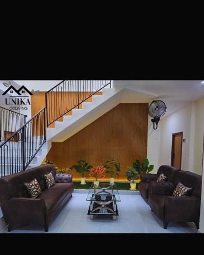 a living room with two couches and a staircase at Unika Coliving Vibes Syariah in Sultan Syarif Kasim II International Airport