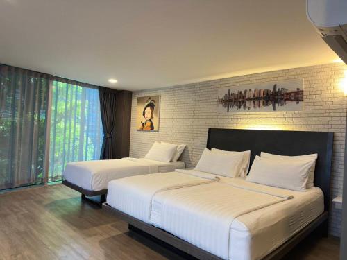 two beds in a hotel room with two beds at BB Glass House Pattanakrn บีบี กลาสเฮ้าส์ พัฒนาการ in Bangkok
