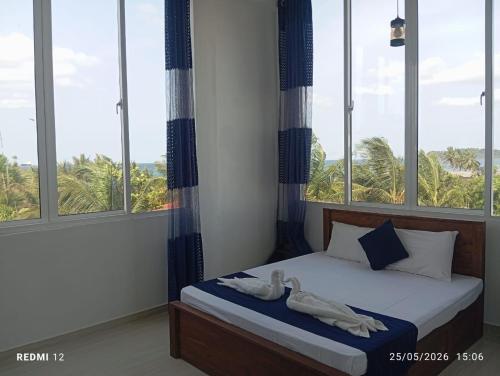 a bedroom with windows and a bed with towels on it at Trinco Star Hotel in Trincomalee