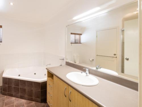 a bathroom with a sink and a bath tub and a mirror at NRMA Angourie Resort, Yamba in Yamba