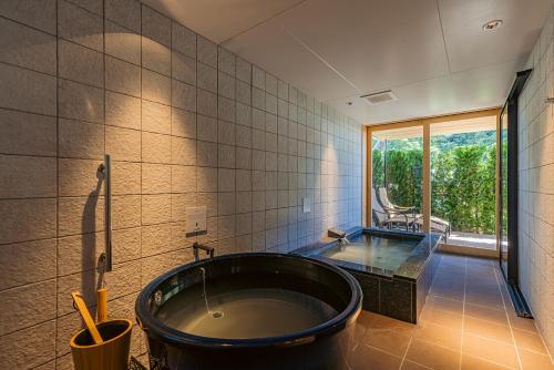 a bathroom with a large black tub and a window at みささ in Kyonan