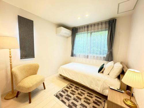 a bedroom with a bed and a chair and a window at Akikawa Koshi 1 プレミアム鉄骨 一棟貸切ヴィラ in Yuge