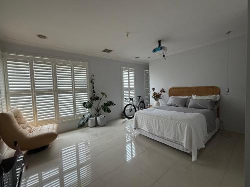 a white bedroom with a bed and a chair at Sunnyhome in Truganina
