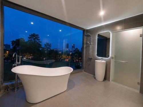 a bathroom with a bath tub and a large window at B&N HOTEL Hải Tiến in Mỹ Ðuc