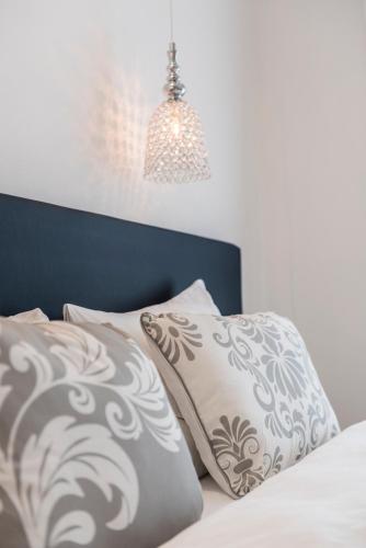 a bed with white pillows and a blue head board at M-Loft merangardenvilla in Merano