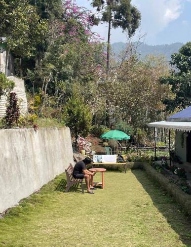 a person sitting at a table in a garden at Pakha Dhim Heritage Homestay in Namchi