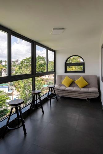 a living room with a couch and some windows at The Node Homestay & Apartment in Xuan An