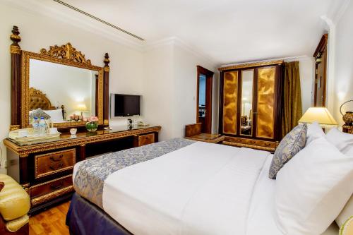 a bedroom with a large white bed and a mirror at Grand Excelsior Hotel - Bur Dubai in Dubai