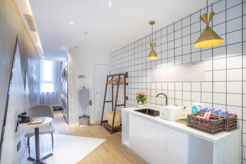 a kitchen with white tiled walls and a sink at 库尔勒孔雀河景观带滨河西路亚朵酒店 in Korla