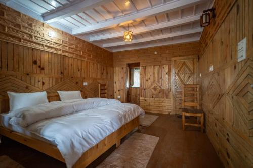 a bedroom with a large bed in a wooden wall at Nandi Roop Homestay in Panuānaula