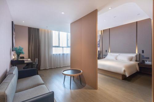 a hotel room with a bed and a couch at 库尔勒孔雀河景观带滨河西路亚朵酒店 in Korla