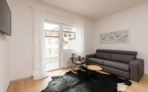 uma sala de estar com um sofá e uma janela em M-Loft merangardenvilla em Merano