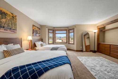 two beds in a hotel room with two windows at Duck Inn Lodge in Whitefish
