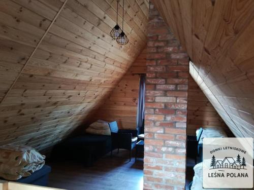 a attic room with a wooden ceiling and a couch at Leśna Polana in Zbiczno
