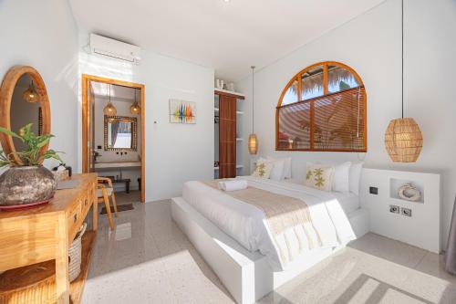 a white bedroom with a bed and a desk at Anatha Villa Uluwatu in Badung