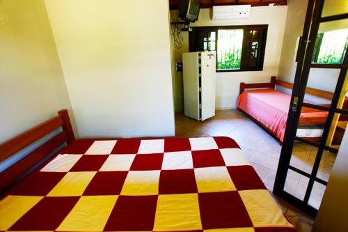 a room with a checkered bed and a room with a refrigerator at Chales Maresias in Maresias