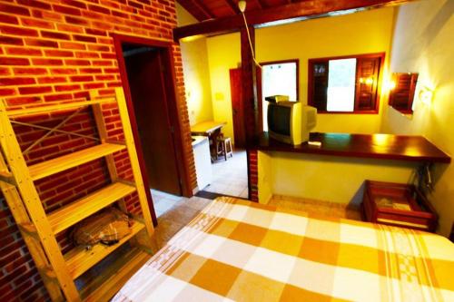 a room with a bed and a brick wall at Chales Maresias in Maresias
