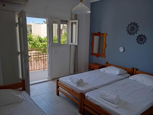 a bedroom with two beds and a door to a balcony at Ξενοδοχείο ΑΡΓΩ in Myrina