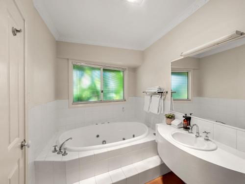 a white bathroom with a tub and a sink at The Arabella Motel in Wollongbar