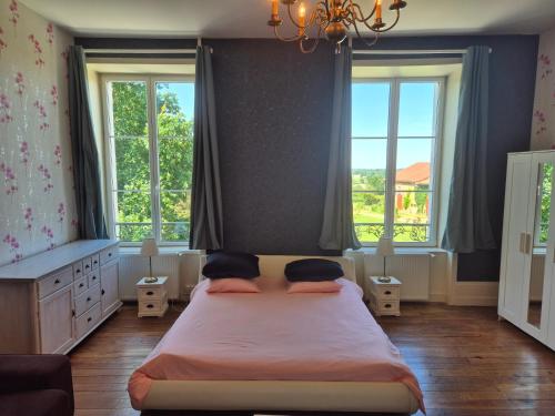 a bedroom with a large bed with two windows at Domaine de Savignac in Chabanais