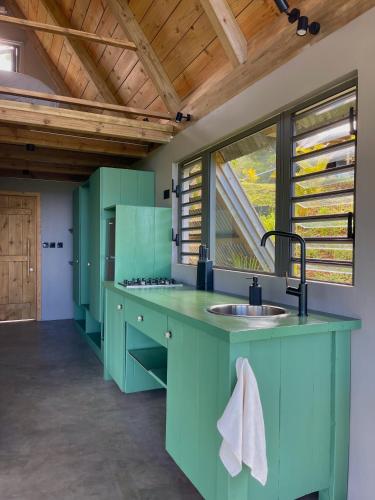 a kitchen with green cabinets and a large window at The A Lodge in Grand Sable