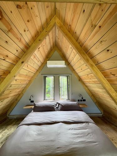 a bed in a room with a wooden ceiling at The A Lodge in Grand Sable