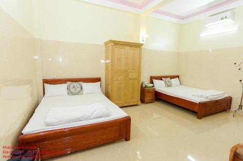 a bedroom with two beds and a wooden cabinet at Khách Sạn Cao Hải in Cao Bằng