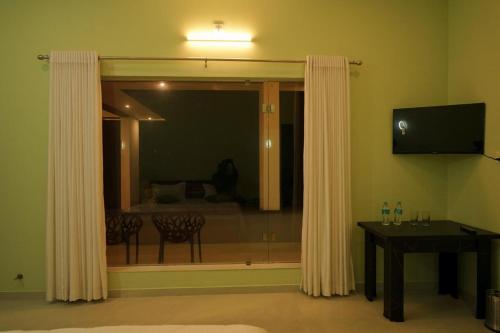 a room with a window with a table and a television at The Calm County Homestay in Mānantoddy