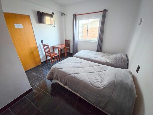 a room with two beds and a table and a window at Virginia hotel in La Quiaca